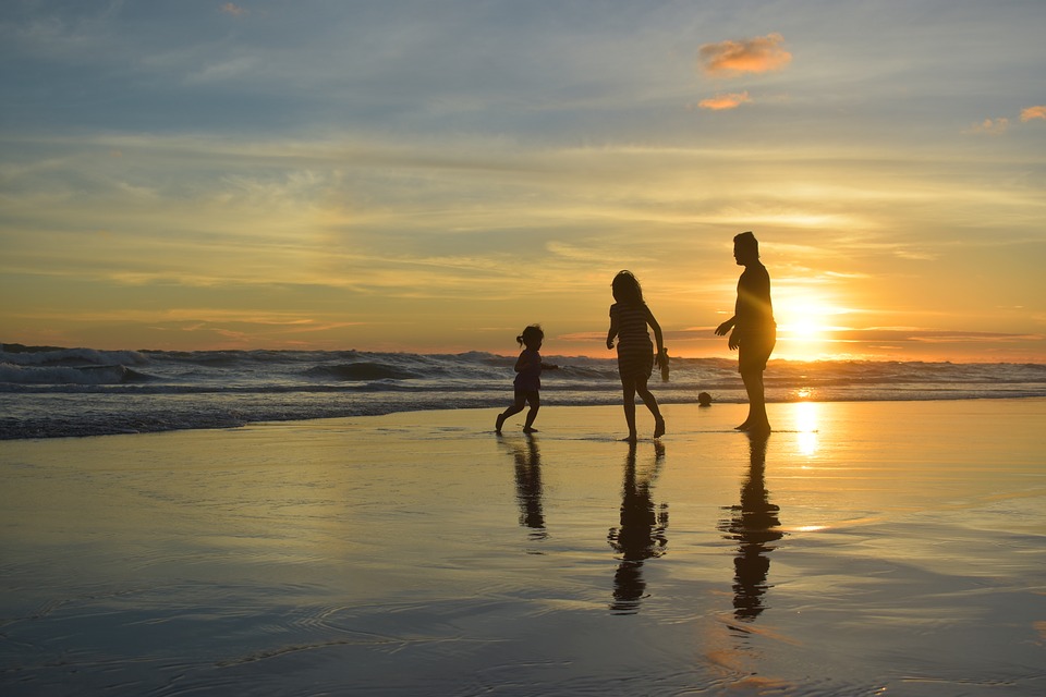 family playing at the beach at sunset